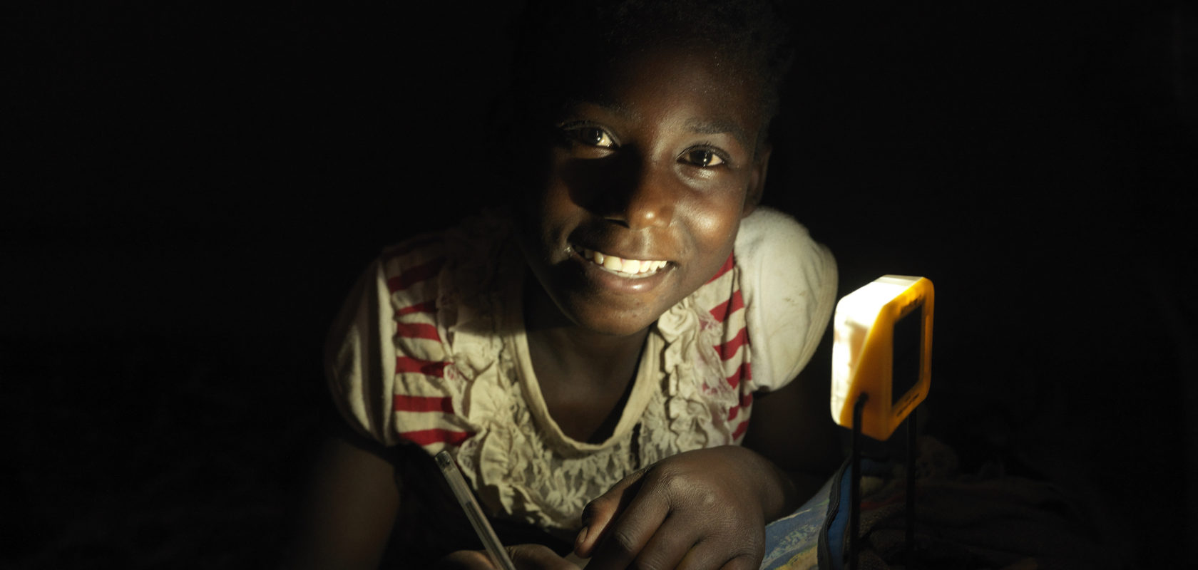 Agnes completes her home work under solar light in her rural Zambien home.