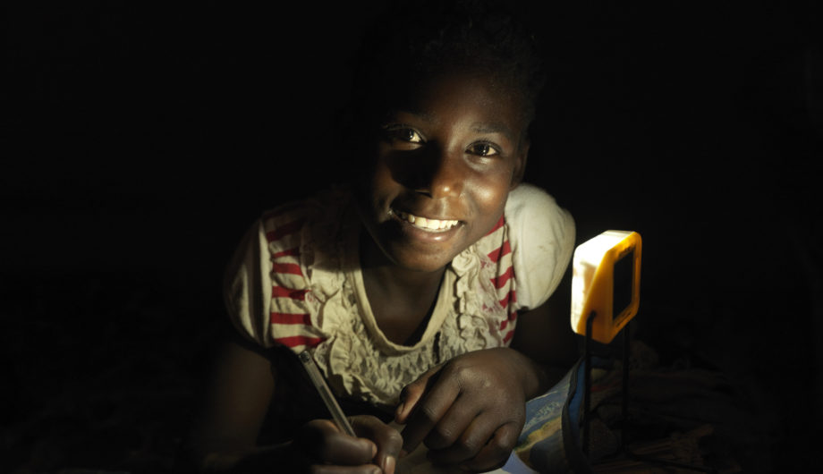 Agnes completes her home work under solar light in her rural Zambien home.