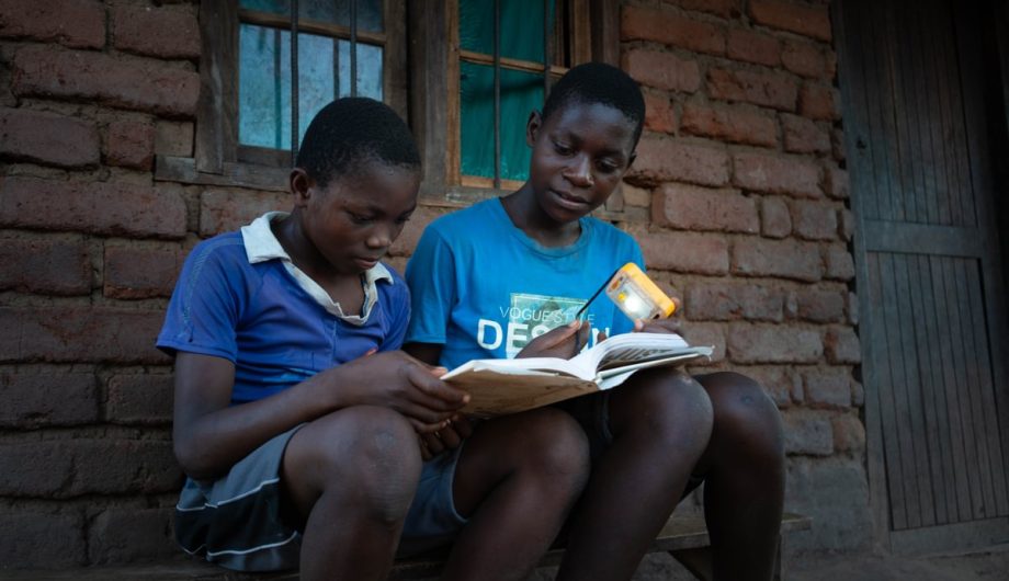Dalitso reads with his friend by the power of a solar light