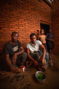 Yohane, Thandiwe and their daughters cook with the light from an open straw fire.