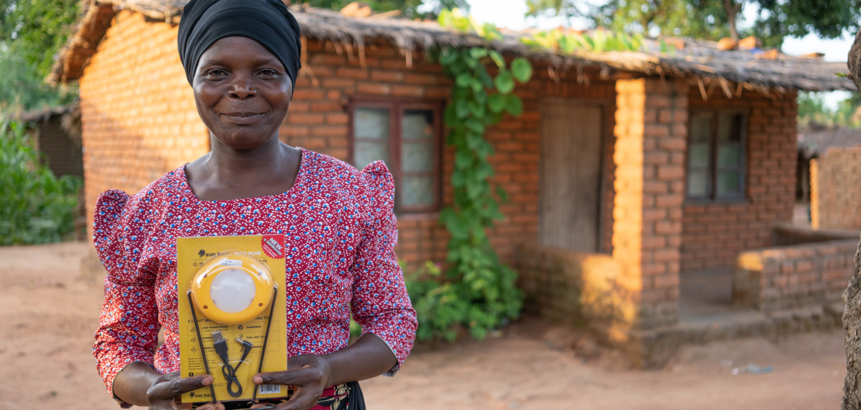 Eness is standing out the front of her house, holding a solar light, smiling