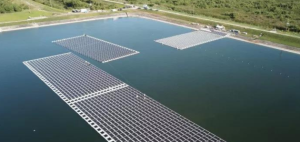 Three large solar panels are floating in a reservoir of water, surrounded by trees. 