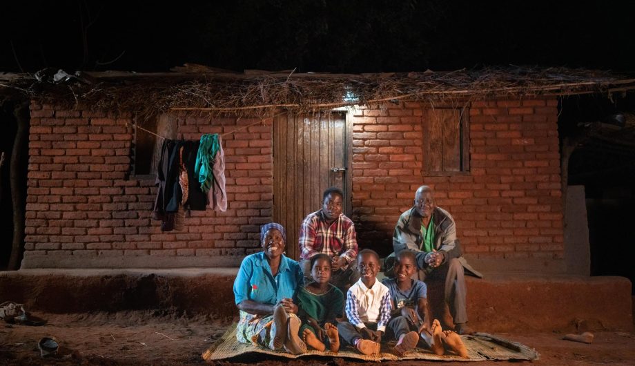 John January and his family sit outside their home under their solar light